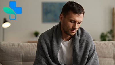 Мужчина укутанный в одеяло грустно смотрит вниз