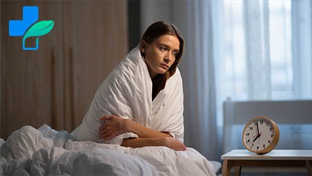 Девушка сидит укутанная в одеяло с бессонницей